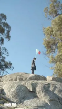 A man holding a balloon on rocks